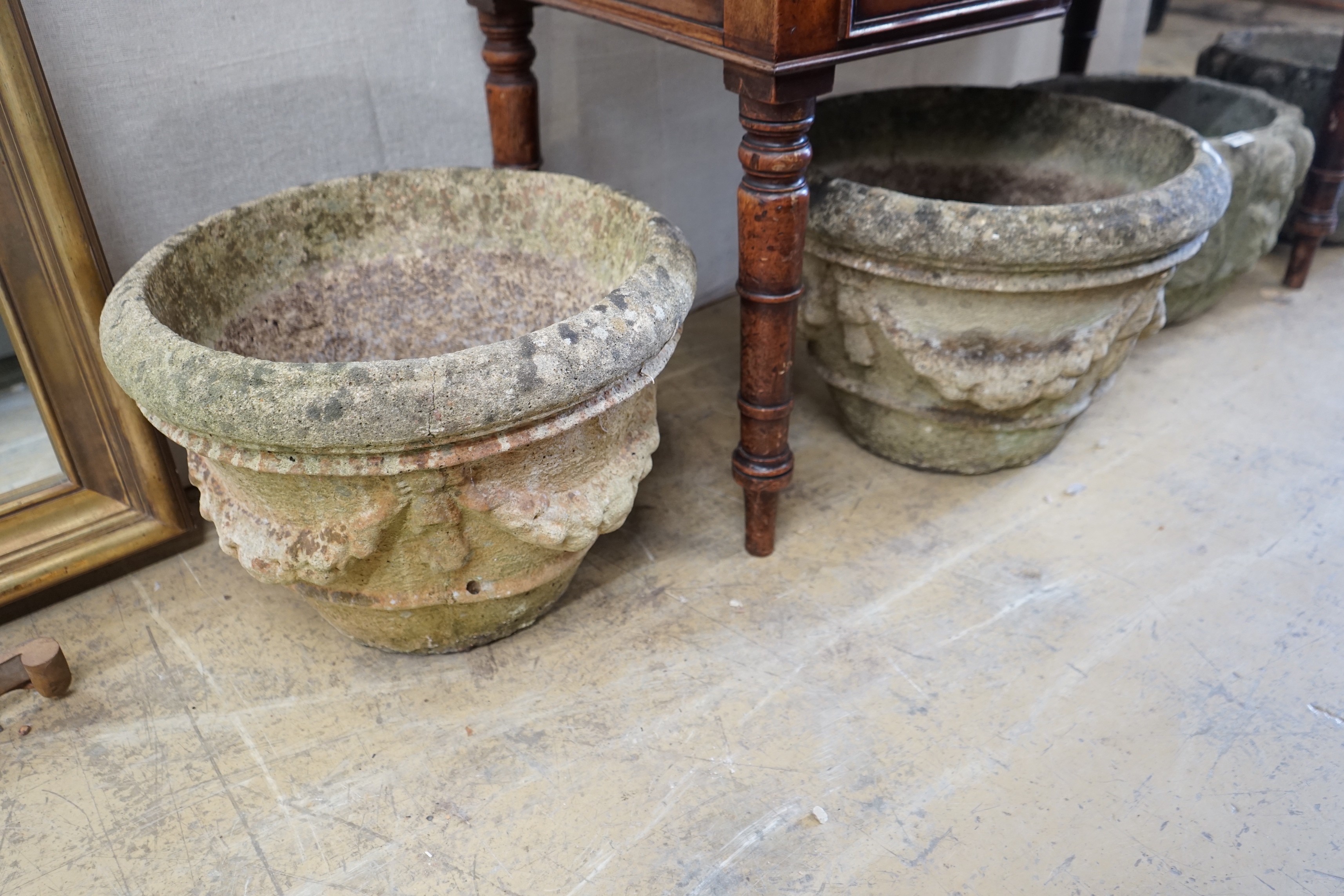 A pair of circular reconstituted stone garden urns with swagged floral bodies diameter 46cm height 33cm